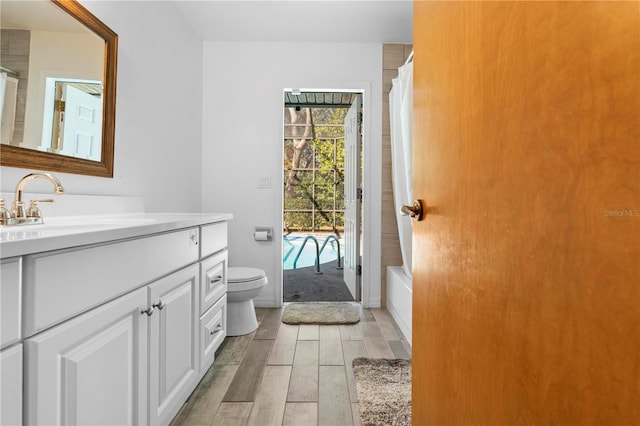 full bathroom with hardwood / wood-style flooring, vanity, toilet, and shower / tub combo