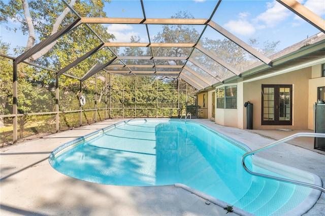 view of pool featuring glass enclosure, a patio area, and french doors