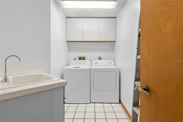 washroom with cabinets, sink, a textured ceiling, light tile patterned flooring, and washing machine and clothes dryer