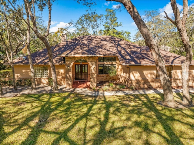 ranch-style home with a front yard and french doors