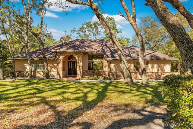 7443 Oak Tree Ln, Spring Hill, FL 34607 - view of front of property with a front lawn, brick siding, a chimney, and stucco siding