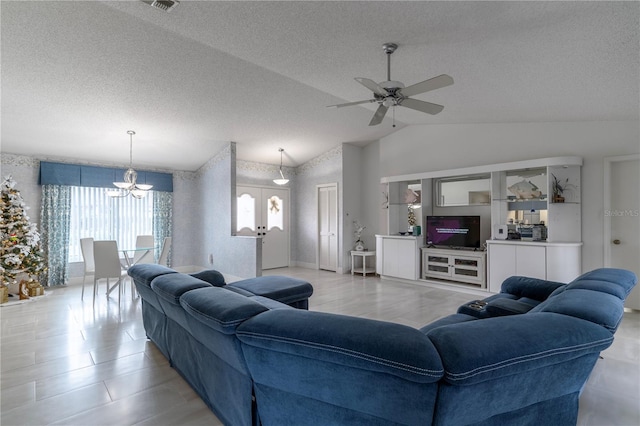 living room featuring ceiling fan with notable chandelier, french doors, a textured ceiling, and vaulted ceiling