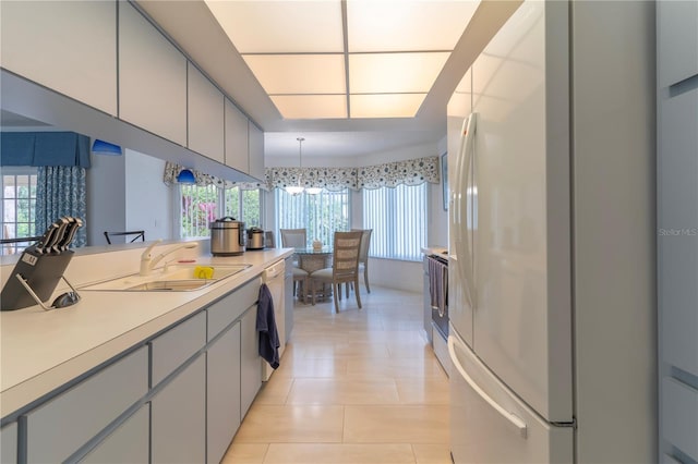 kitchen with stainless steel range with electric cooktop, white refrigerator, sink, light tile patterned floors, and decorative light fixtures