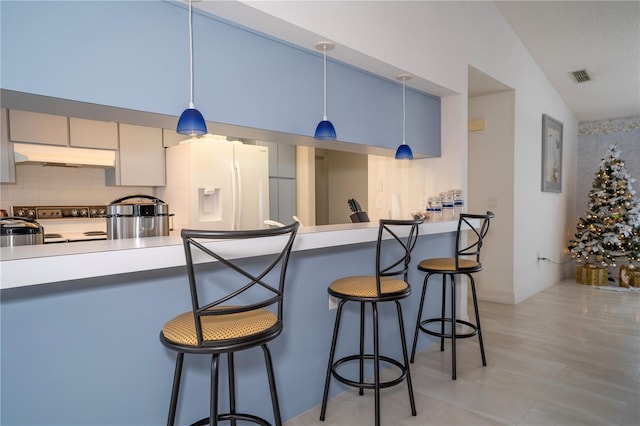 kitchen featuring a kitchen breakfast bar, tasteful backsplash, white refrigerator with ice dispenser, pendant lighting, and lofted ceiling