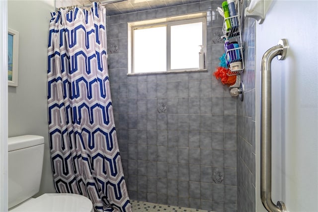 bathroom with a tile shower and toilet