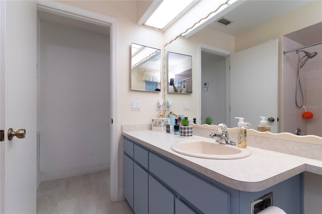 bathroom featuring a tile shower, tile patterned flooring, and vanity