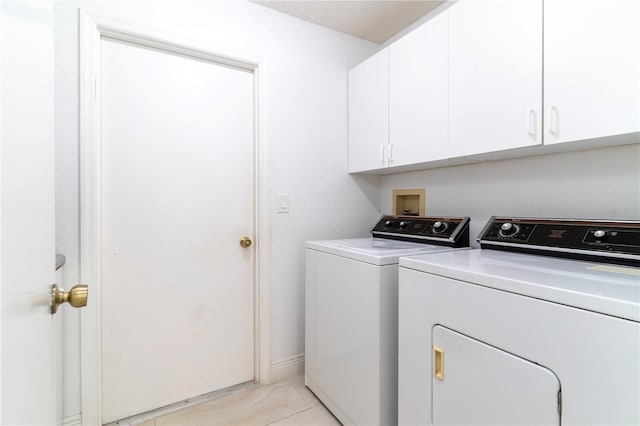 clothes washing area with washing machine and clothes dryer and cabinets