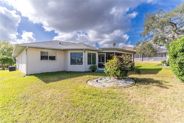 rear view of property featuring a lawn and central AC