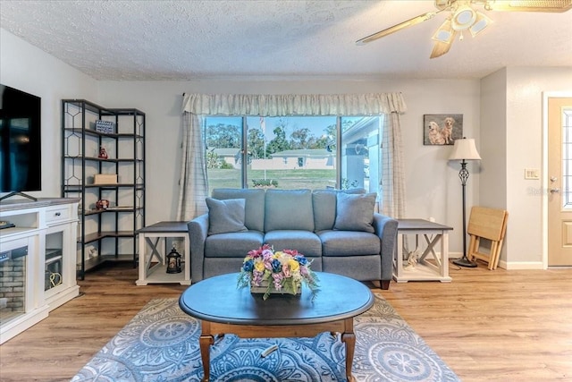 living room with ceiling fan, a textured ceiling, and hardwood / wood-style flooring