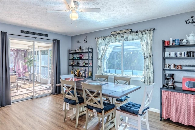 dining area featuring ceiling fan, wood-type flooring, and a textured ceiling