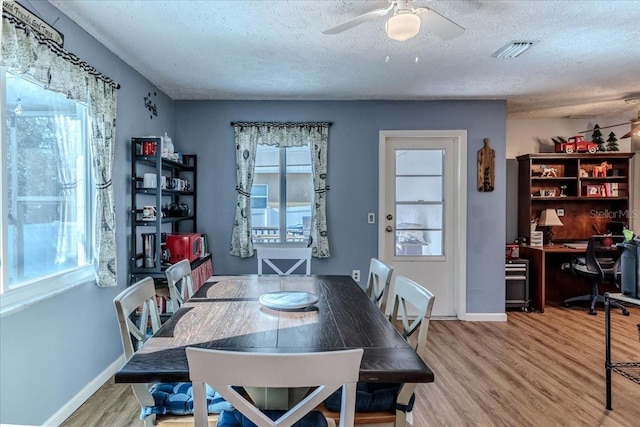 dining area featuring a textured ceiling, a wealth of natural light, and hardwood / wood-style flooring