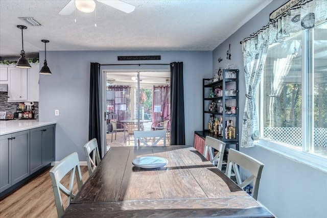 dining space featuring ceiling fan, light hardwood / wood-style flooring, and a textured ceiling