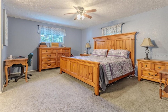 bedroom with ceiling fan, light colored carpet, and a textured ceiling