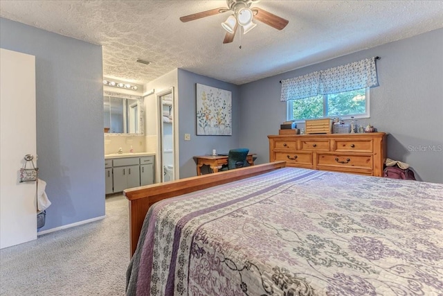 carpeted bedroom with ceiling fan, ensuite bathroom, sink, and a textured ceiling