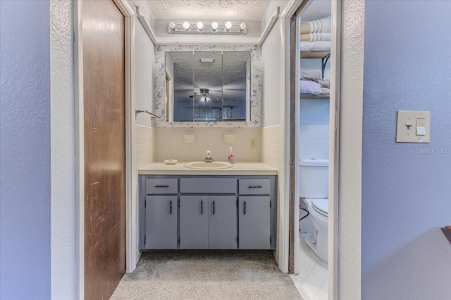 bathroom with vanity, toilet, and a textured ceiling