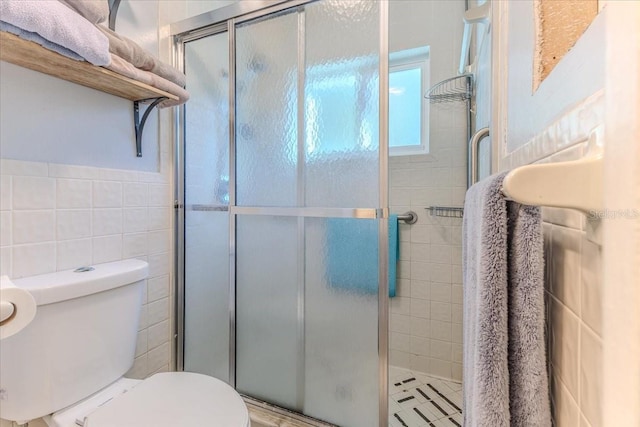 bathroom featuring an enclosed shower, tile walls, and toilet