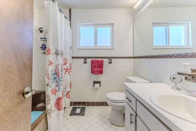 bathroom with curtained shower, tile walls, tile patterned flooring, vanity, and toilet