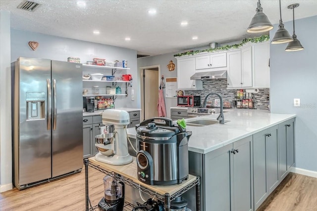 kitchen with stainless steel refrigerator with ice dispenser, white cabinetry, light wood-type flooring, kitchen peninsula, and pendant lighting