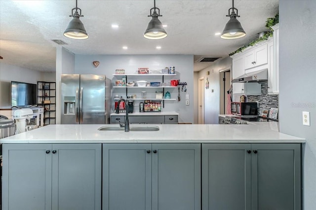 kitchen with stainless steel fridge, sink, hanging light fixtures, and backsplash