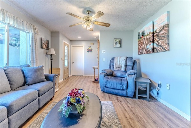 living room with ceiling fan, light hardwood / wood-style flooring, and a textured ceiling