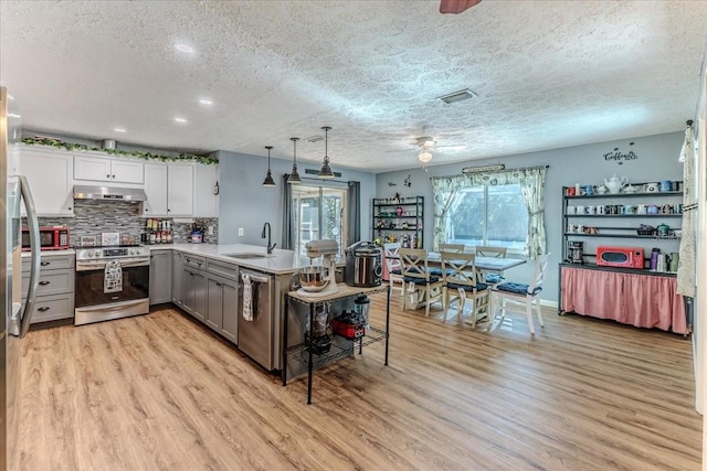 kitchen featuring pendant lighting, sink, stainless steel appliances, white cabinets, and kitchen peninsula