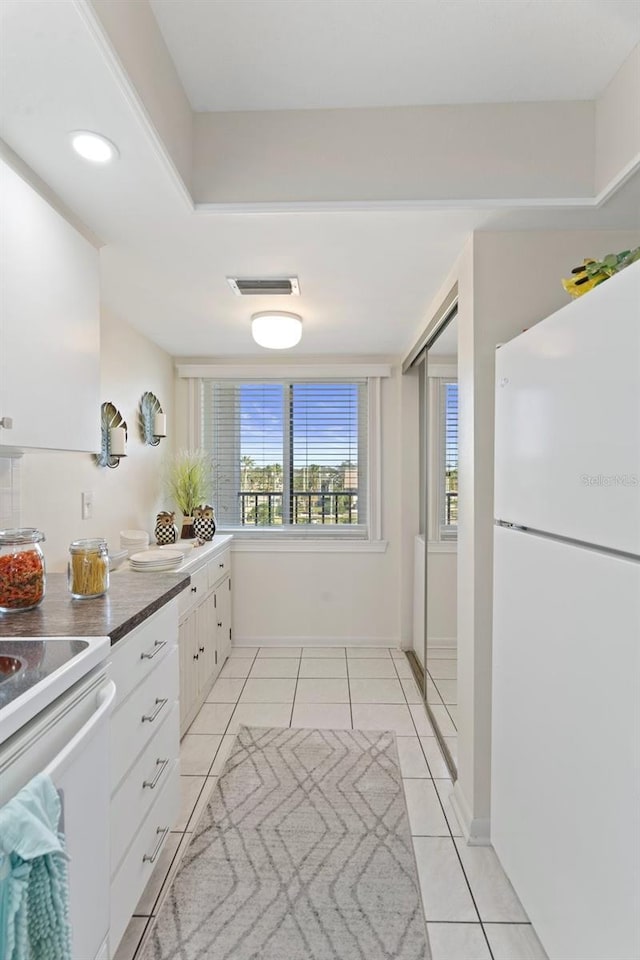 kitchen featuring white cabinetry, light tile patterned floors, and white appliances