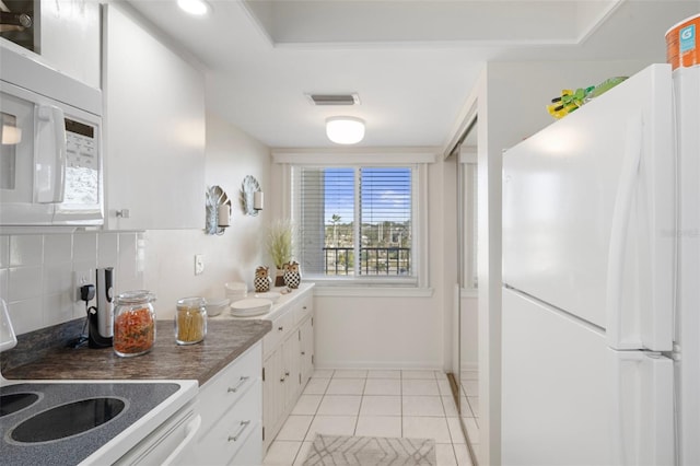 kitchen with white cabinets, white appliances, light tile patterned floors, and tasteful backsplash