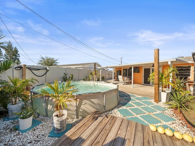 wooden terrace with a fenced in pool and a patio area