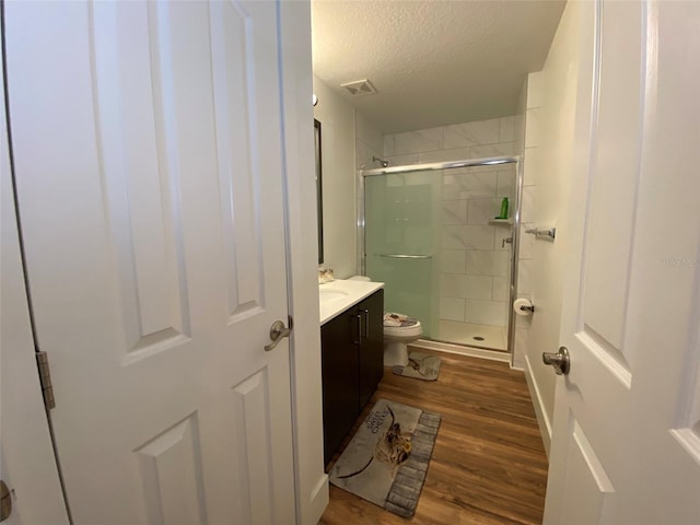 bathroom featuring a textured ceiling, vanity, wood-type flooring, and a shower with door