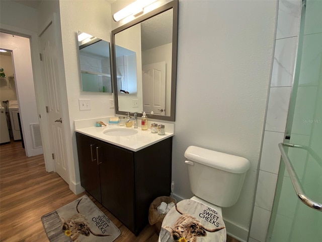 bathroom featuring vanity, wood-type flooring, a shower with shower door, and toilet