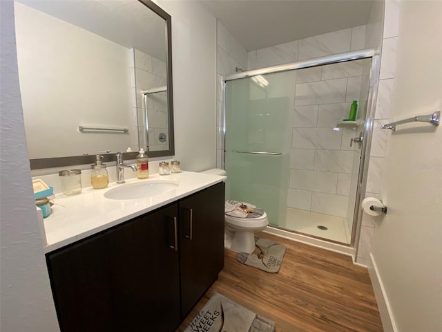 bathroom with hardwood / wood-style floors, vanity, a shower with shower door, and toilet