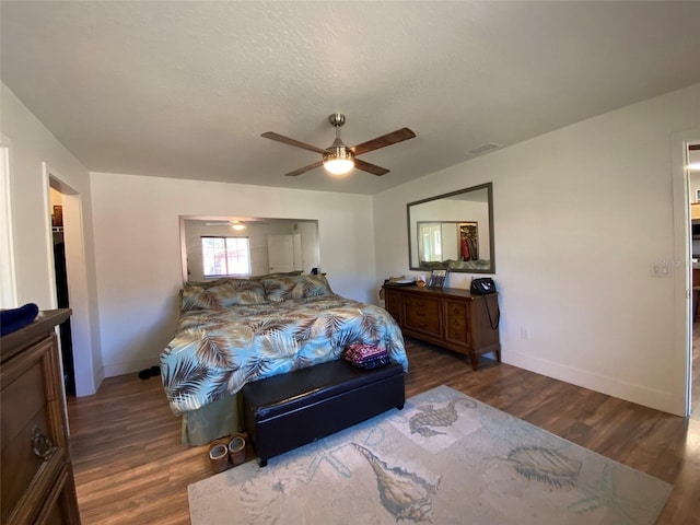 bedroom with a textured ceiling, ceiling fan, and dark hardwood / wood-style floors