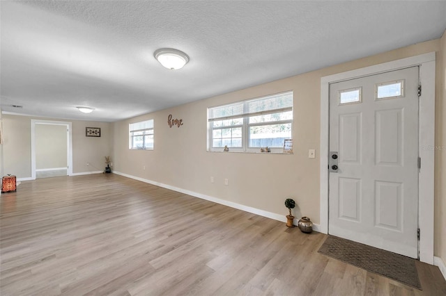 foyer entrance with light hardwood / wood-style flooring and a textured ceiling