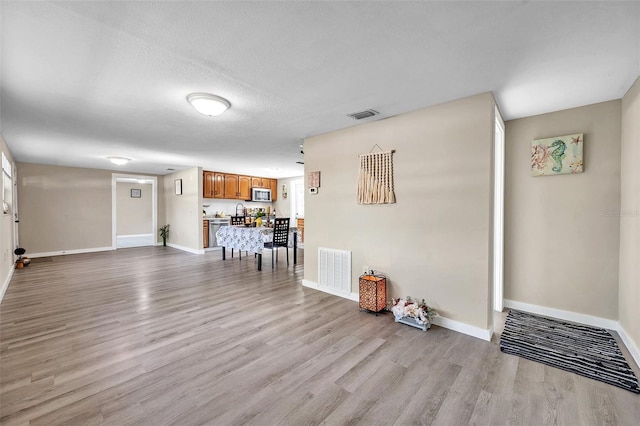 unfurnished living room with a textured ceiling and light wood-type flooring