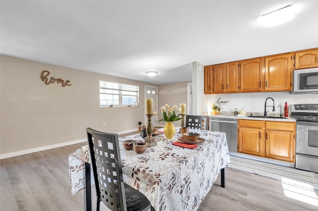 dining space with a textured ceiling, light hardwood / wood-style floors, and sink