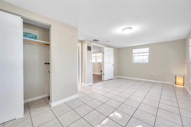 unfurnished bedroom featuring a closet, light tile patterned floors, and a textured ceiling