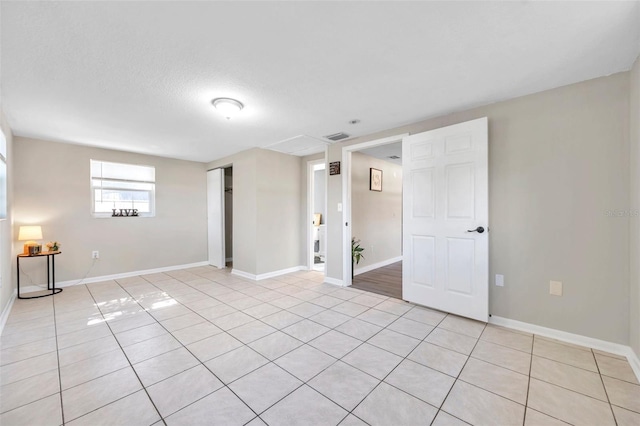 tiled empty room featuring a textured ceiling