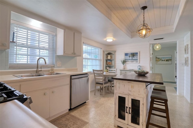 kitchen with sink, stainless steel appliances, a kitchen island, decorative light fixtures, and white cabinets