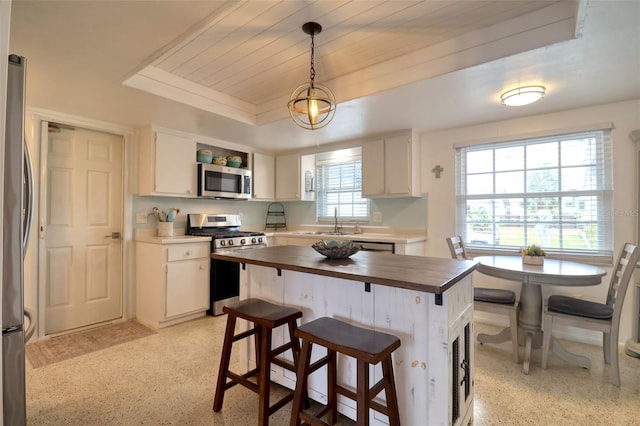 kitchen with white cabinets, stainless steel appliances, hanging light fixtures, and wooden counters