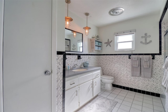 bathroom featuring tile patterned flooring, vanity, toilet, and tile walls