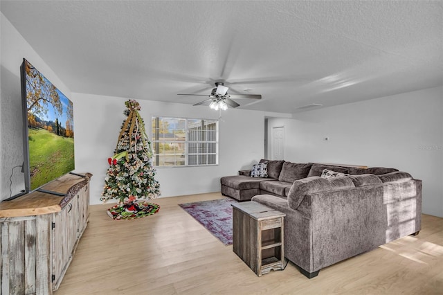 living room featuring a textured ceiling, light wood-type flooring, and ceiling fan