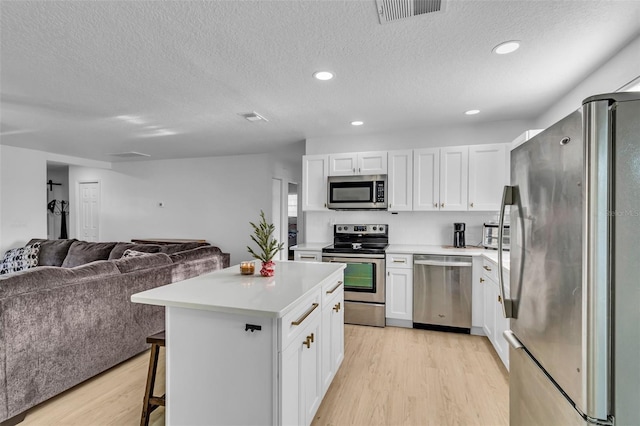 kitchen with white cabinetry, a center island, light wood-type flooring, and appliances with stainless steel finishes