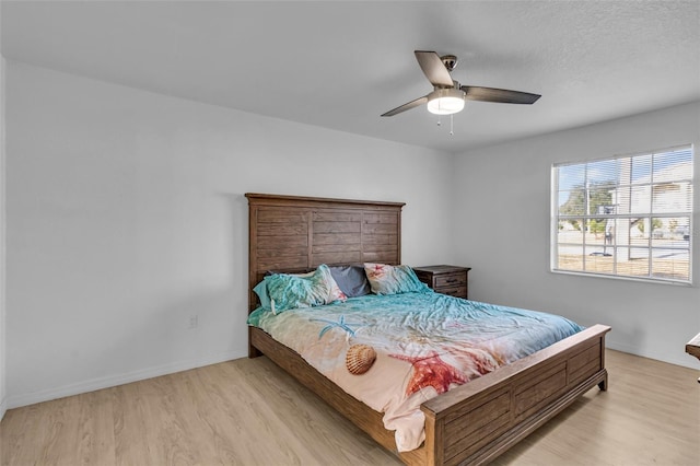 bedroom with a textured ceiling, light hardwood / wood-style floors, and ceiling fan