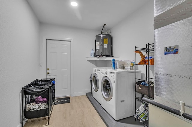 clothes washing area with independent washer and dryer, light wood-type flooring, and water heater