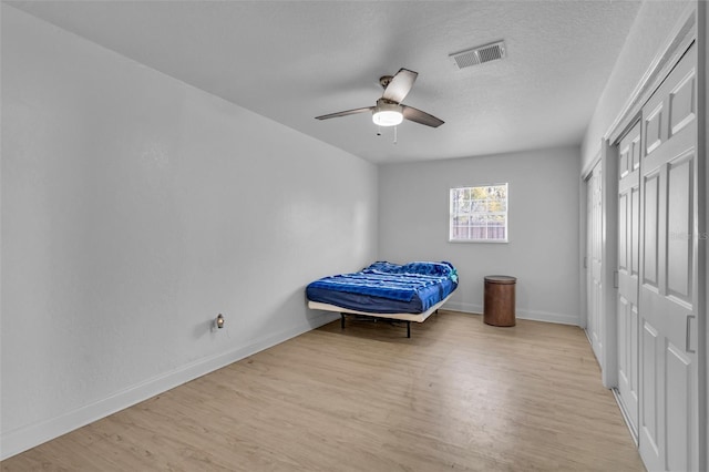 bedroom with ceiling fan, light hardwood / wood-style flooring, and a textured ceiling