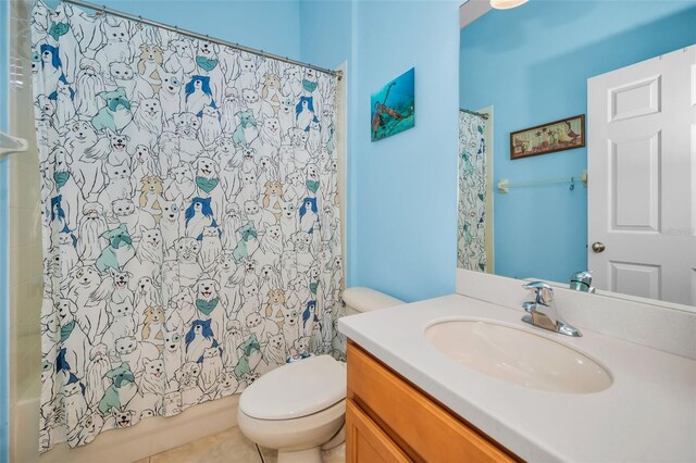 bathroom with toilet, tile patterned flooring, shower / bath combo with shower curtain, and vanity