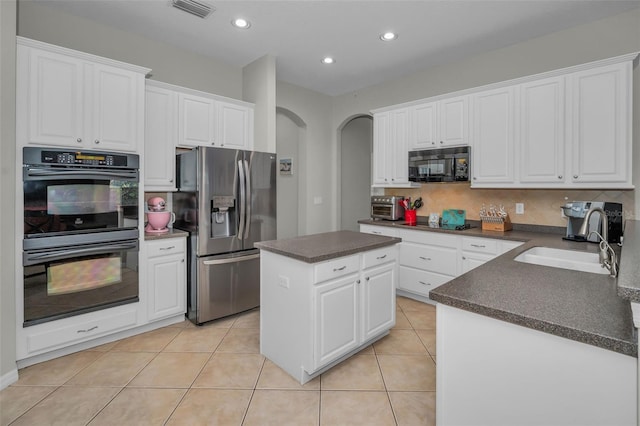 11645 Belle Haven Dr, New Port Richey, FL 34654 - kitchen with black appliances, a sink, dark countertops, arched walkways, and white cabinetry