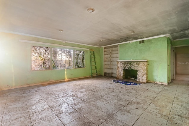 unfurnished living room with a stone fireplace and ornamental molding