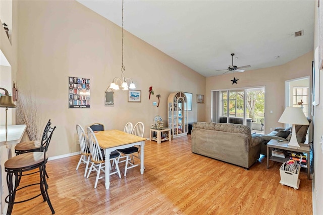 dining space with ceiling fan with notable chandelier and light wood-type flooring