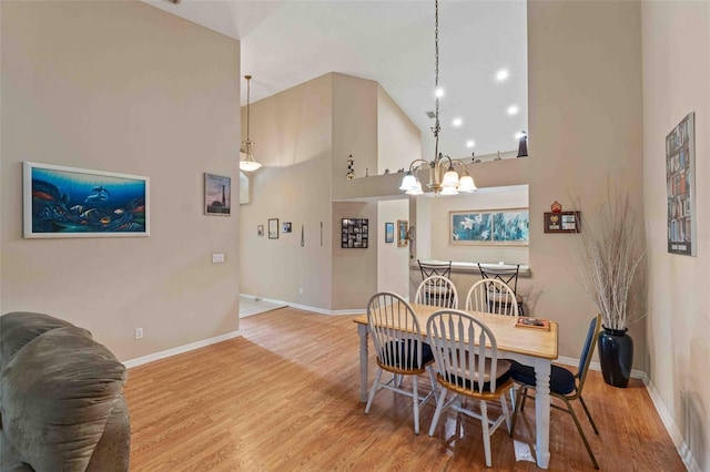 dining space with hardwood / wood-style flooring, a towering ceiling, and an inviting chandelier